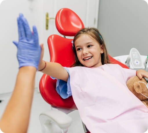 Child in dental chair giving dentist a high five