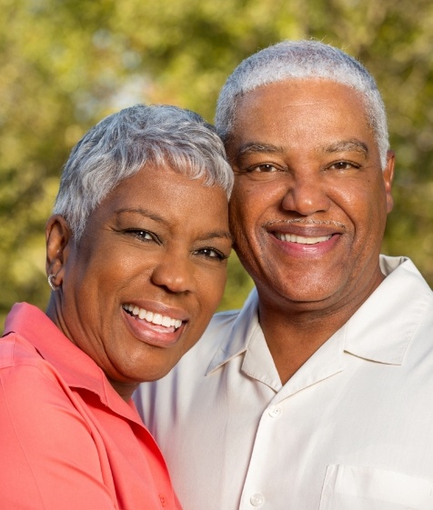 Man and woman smiling after dental crown and bridge restorations