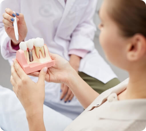 Dentist and dentistry patient looking at dental implant model