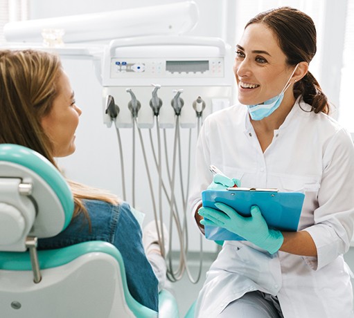 Dentist smiling at patient while taking notes on clipboard